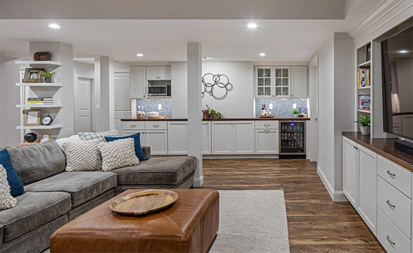 image of a refinished basement showing lvp flooring white cabinetry shelving tv and couch